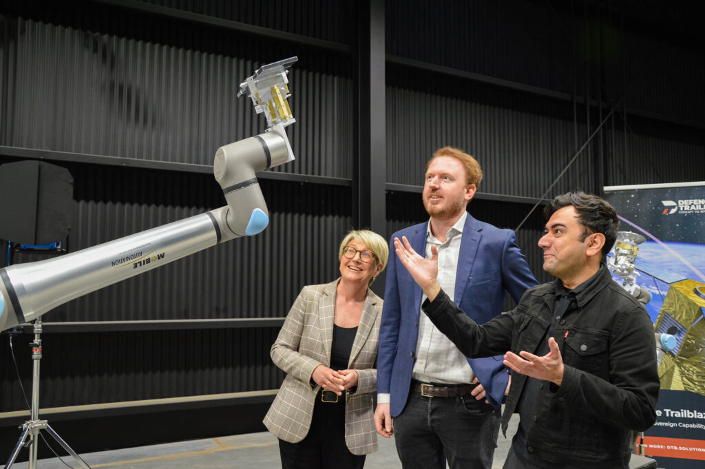 Dr Margaret Law (Defence Trailblazer), Mark Ramsey (Space Machines Company) and Mohsi Jawaid (University of Adelaide) in front of the orbital testbed's two robotic arms. 