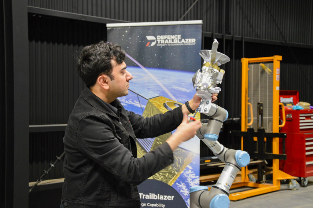 University of Adelaide researcher Mohsi Jawaid with an experimental satellite model attached to the orbital testbed's robotic arm.